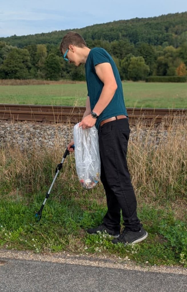 Mann mit Greifzange beim M&uuml;llsammeln